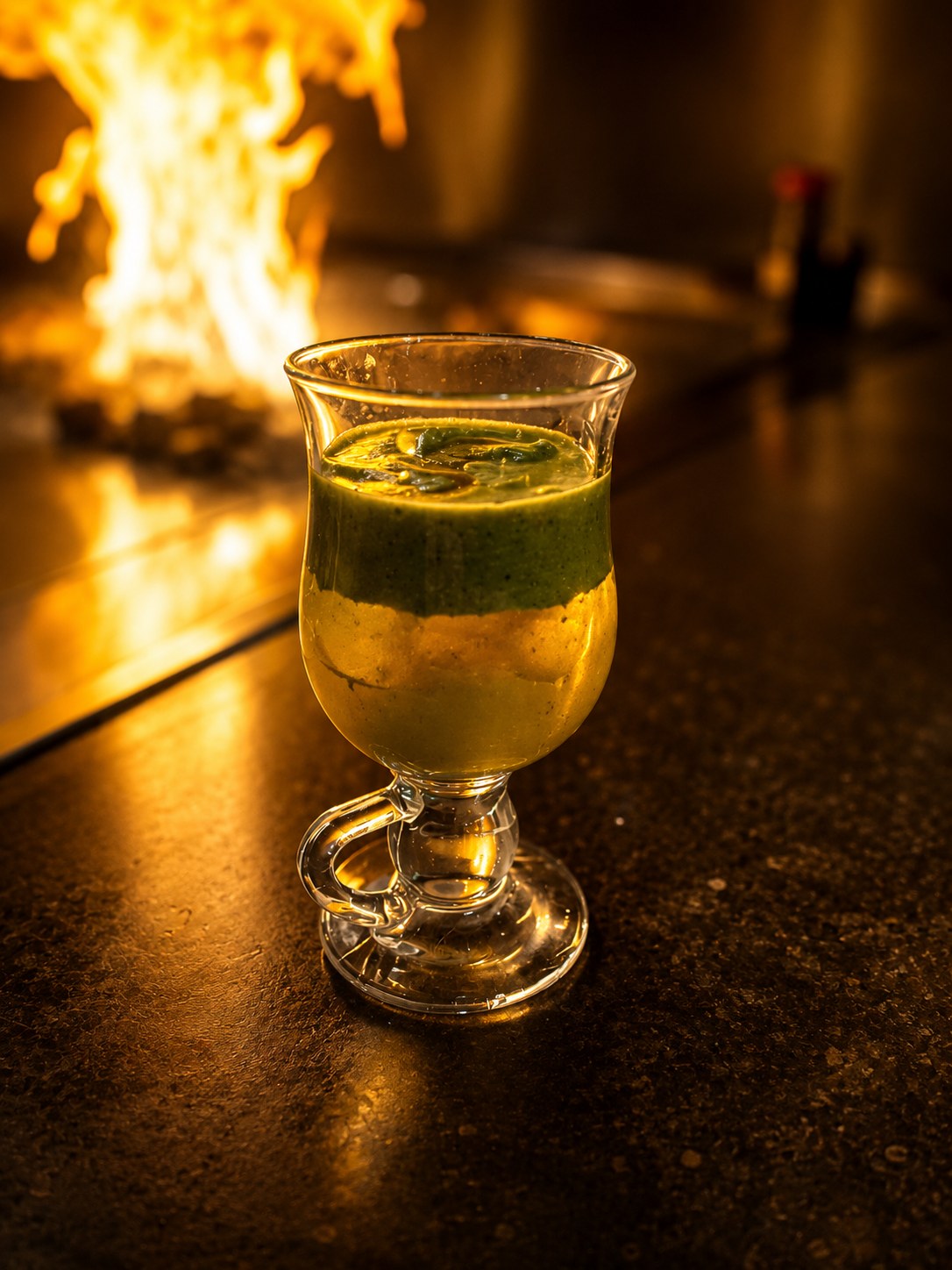 Layered drink beside a flaming Suehiro hibachi grill