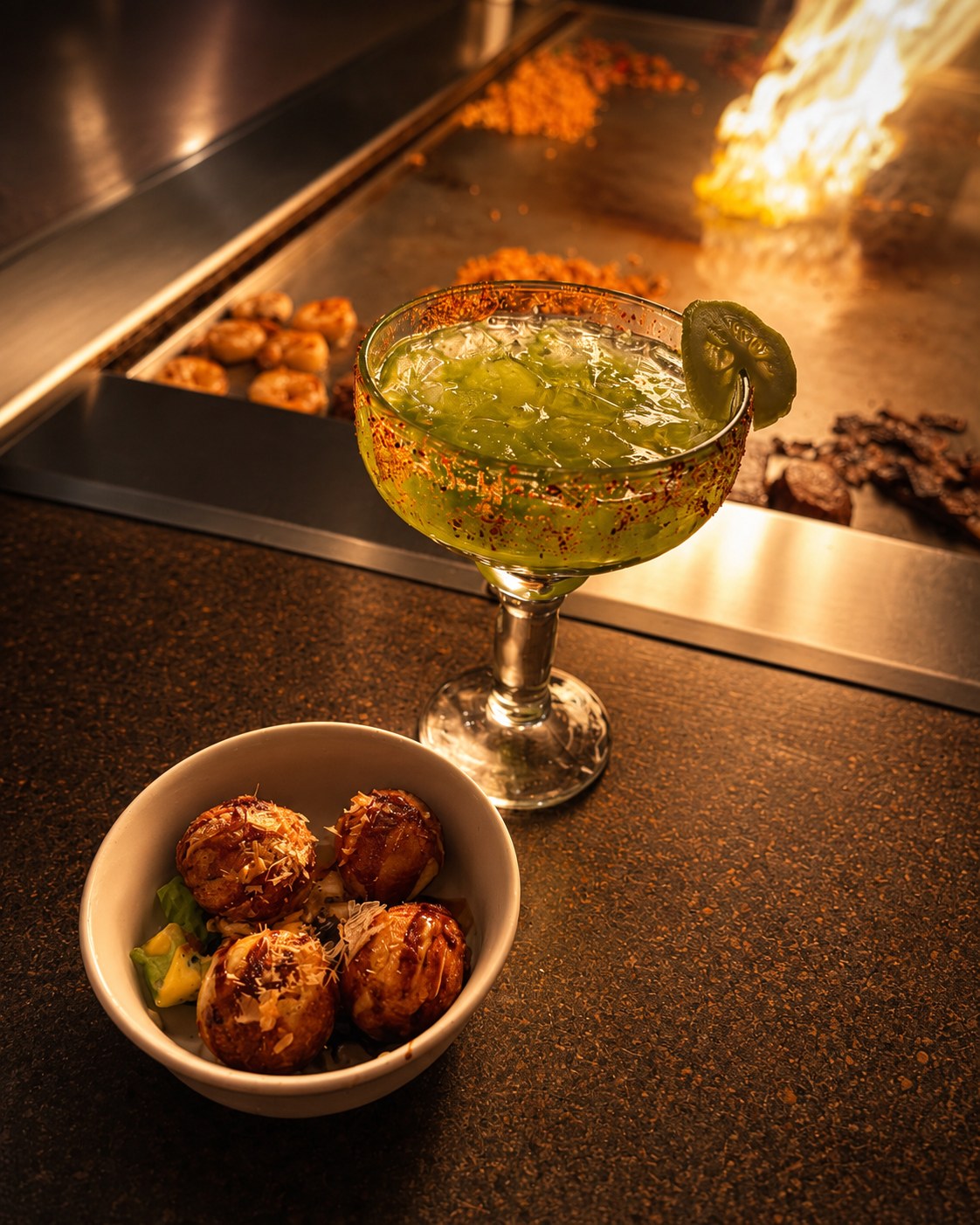 Takoyaki and green cocktail beside the hibachi grill