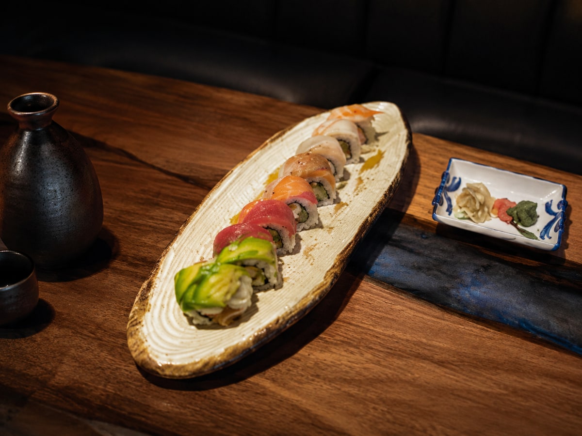 Rainbow sushi roll with avocado, tuna, and salmon on a ceramic plate
