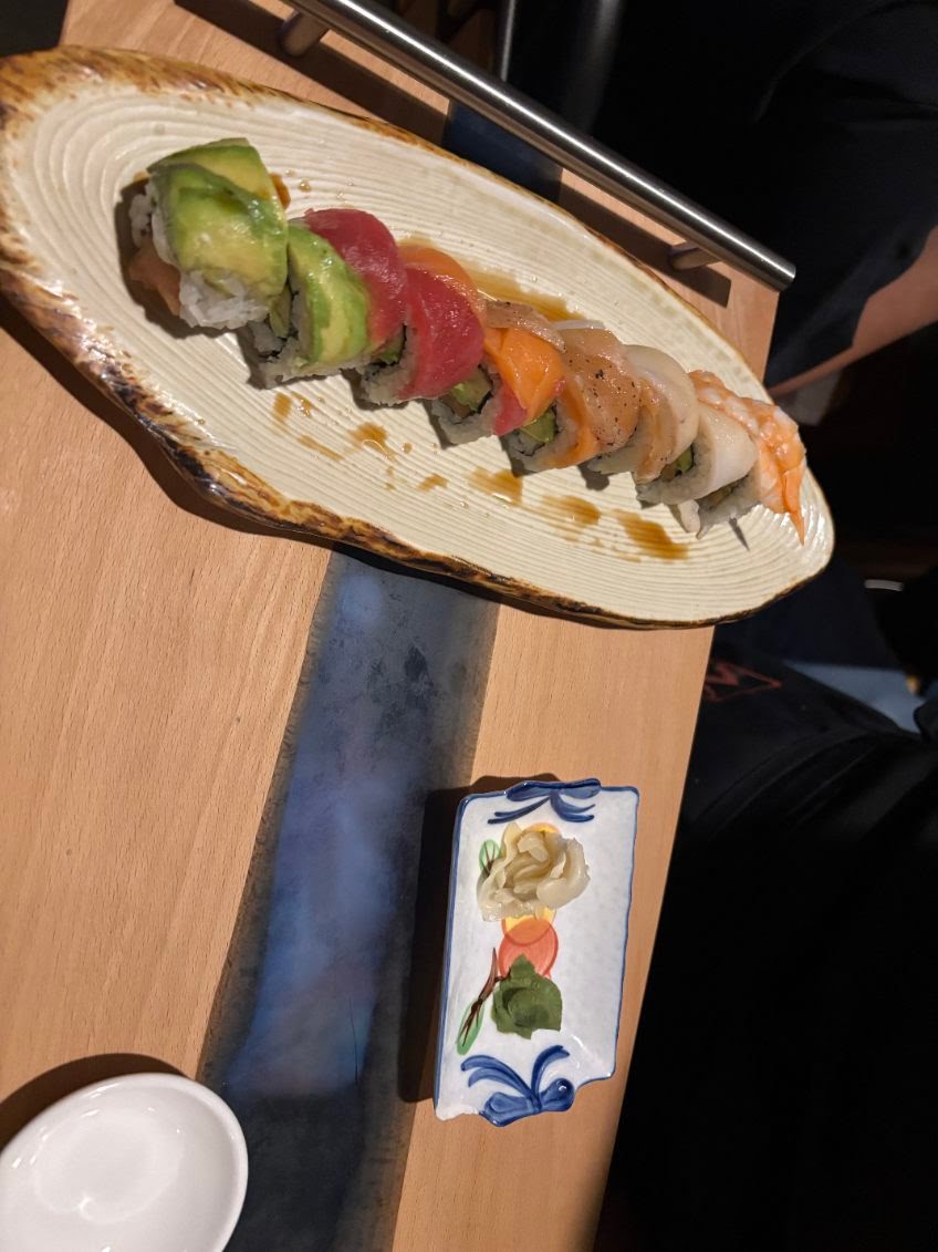 Rainbow sushi roll with avocado, tuna, and salmon on a ceramic plate